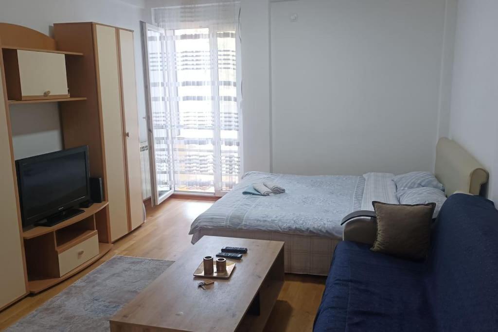 a living room with a bed and a blue couch at Apartman Selma - Bijelo Polje in Bijelo Polje