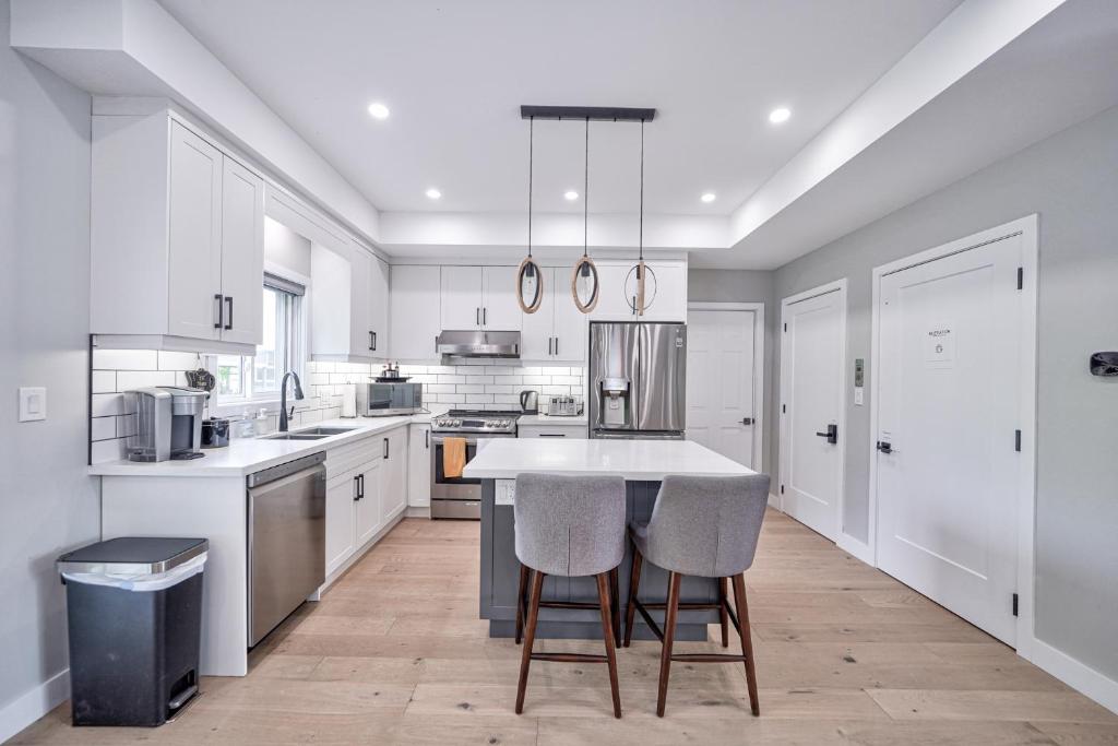 a kitchen with white cabinets and a island with bar stools at Lake view cottage with three ensuites and elevator in Fort Erie