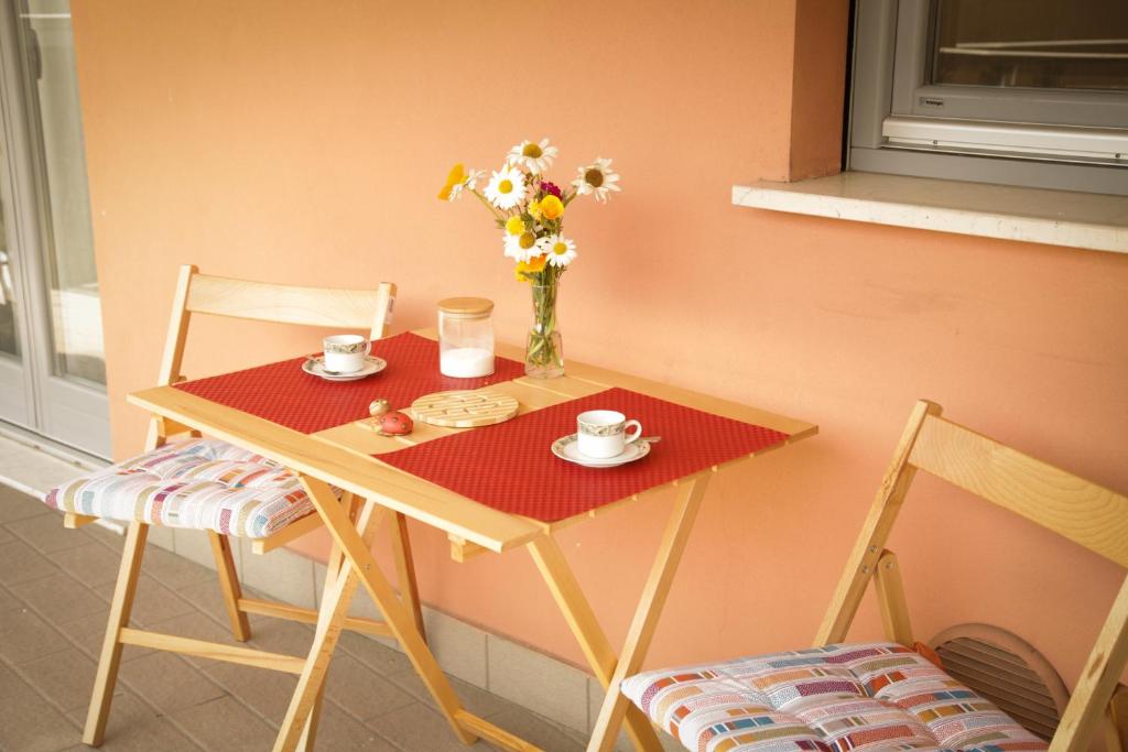 een tafel met twee stoelen en een vaas met bloemen erop bij Sole&Luna Apartment in Trento