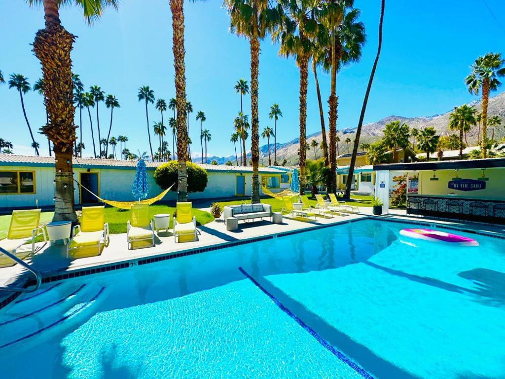 een zwembad met gele stoelen en palmbomen bij A PLACE IN THE SUN Hotel - ADULTS ONLY Big Units, Privacy Gardens & Heated Pool & Spa in 1 Acre Park Prime Location, PET Friendly, TOP Midcentury Modern Boutique Hotel in Palm Springs