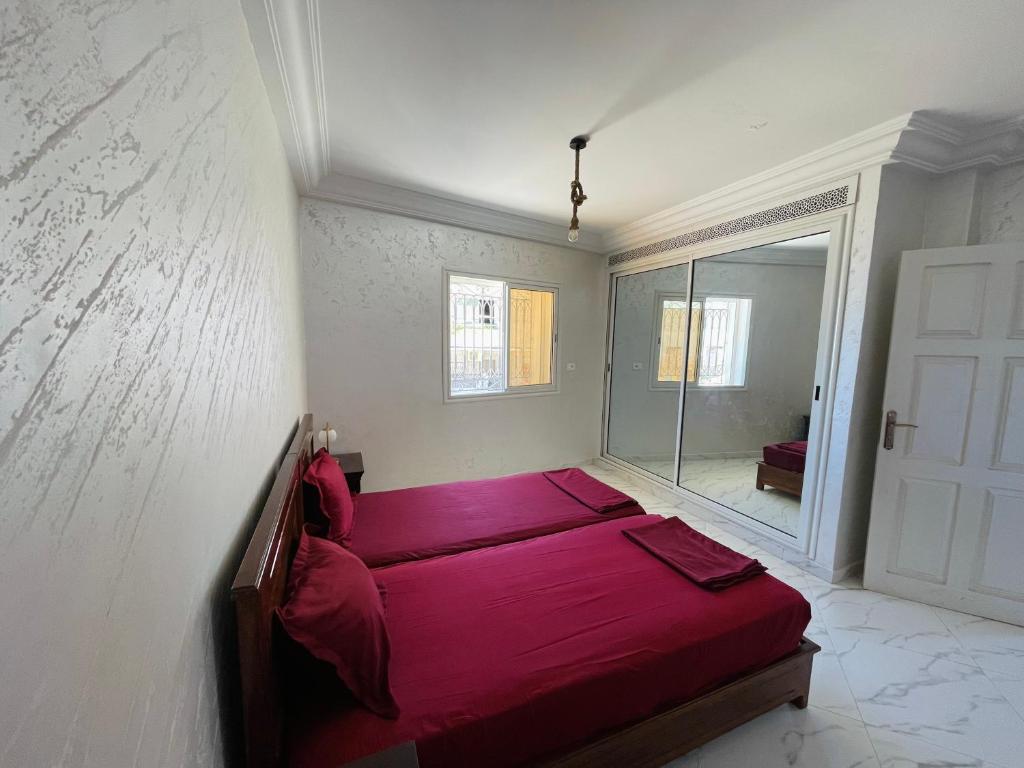 una camera con letto rosso e specchio di Seaside Guest House a Ghār al Milḩ