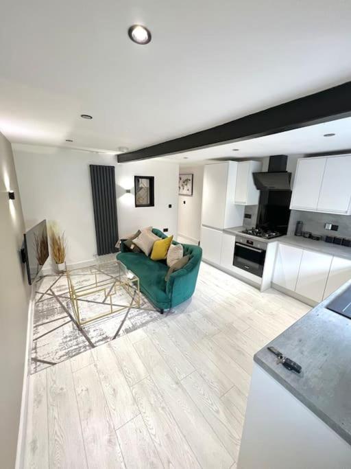 a living room with a green couch and a kitchen at Farsley Cottage in Farsley