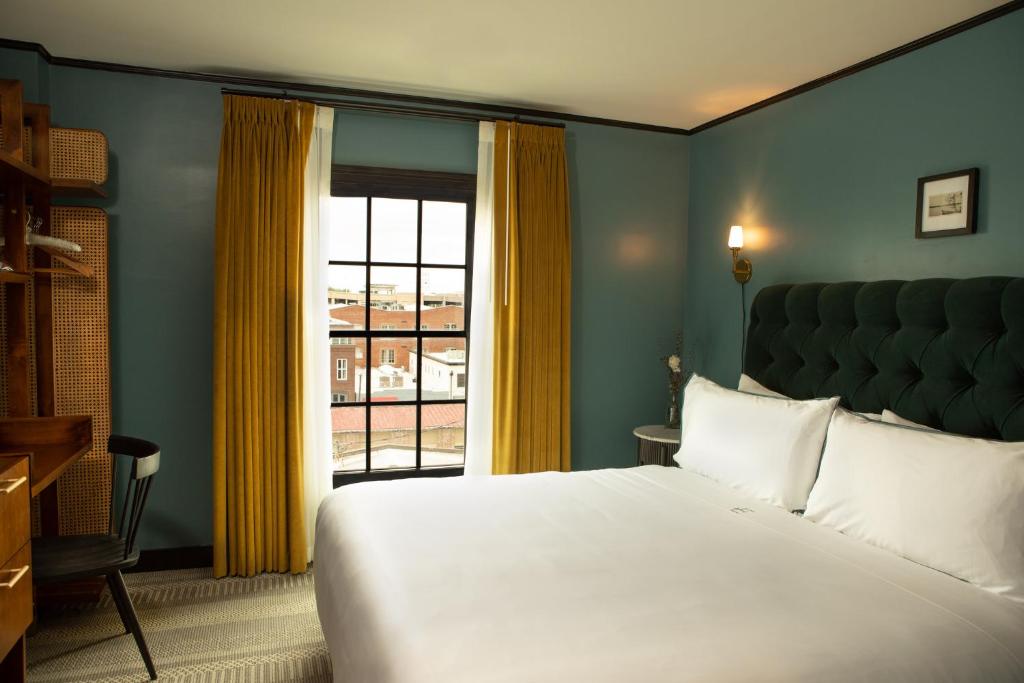 a bedroom with a large bed and a window at Hotel Emeline in Charleston