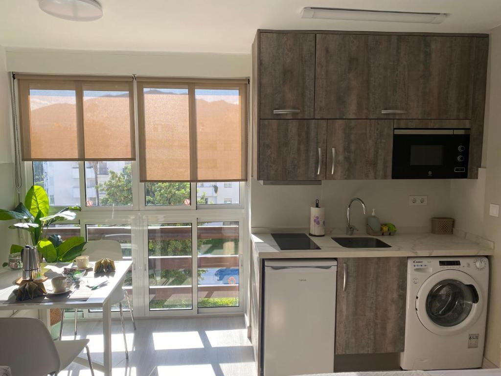 una cucina con armadi in legno e lavastoviglie bianca di Apartamentos Naciones Playa, La Paloma a Benalmádena