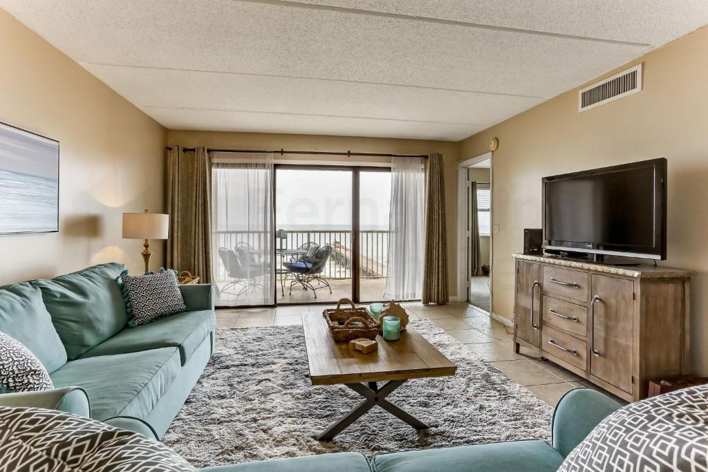 a living room with a blue couch and a tv at Amelia The Sea - 558 ASea in Fernandina Beach