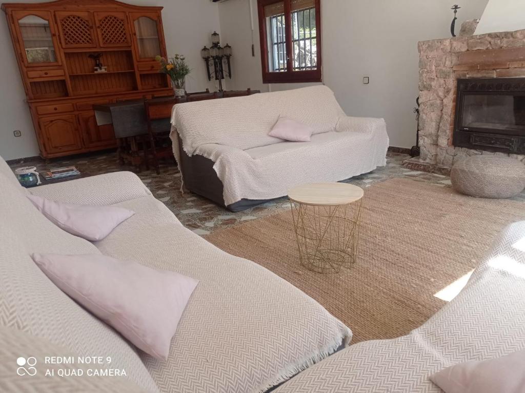 ein Wohnzimmer mit 2 weißen Sofas und einem Kamin in der Unterkunft Casa Calafell in Segur de Calafell