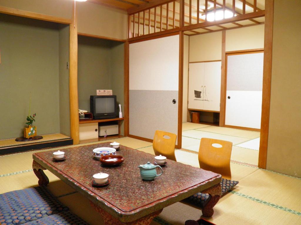 a living room with a table and chairs and a television at 旬樹庵　菊水 in Chikuma