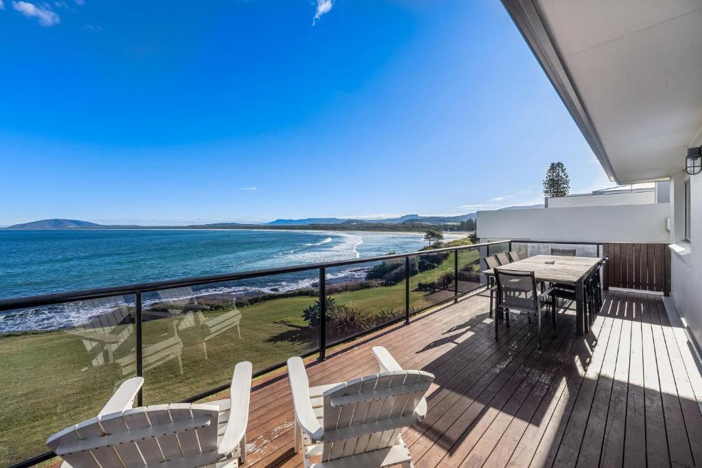 a balcony with a table and chairs and the ocean at Amaroo in Gerroa