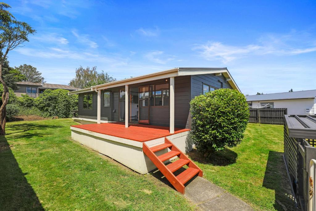 a small house with a red porch on a yard at Be Rude Not To in Rotorua