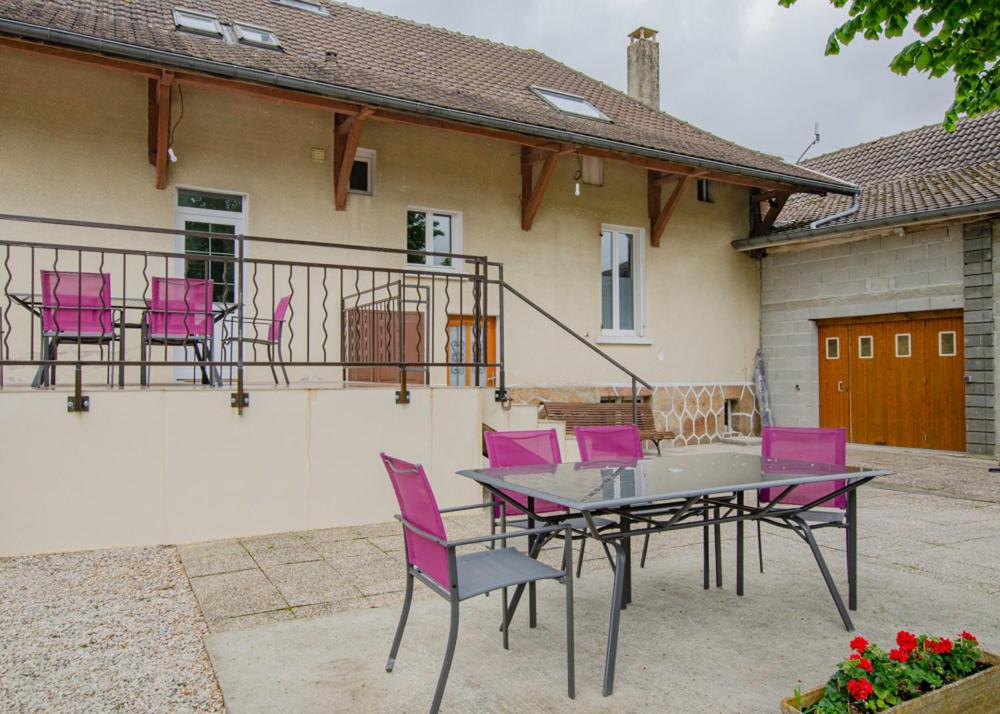 um pátio com cadeiras cor-de-rosa e uma mesa em frente a uma casa em Le gite du cerf 