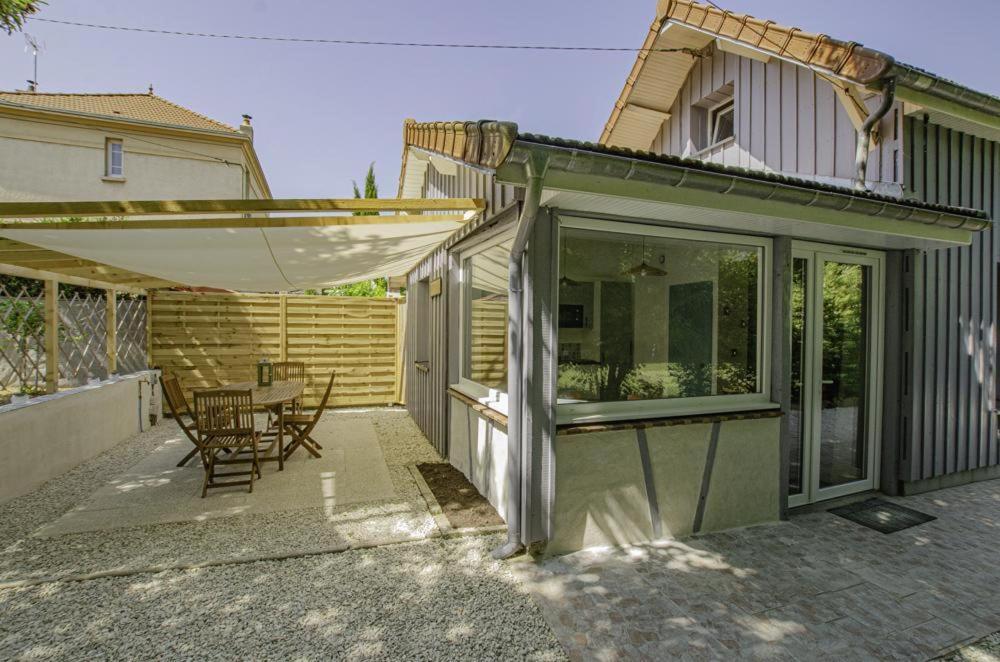 a house with a patio with a table and an umbrella at Le refuge in Saint-Julien-les-Villas