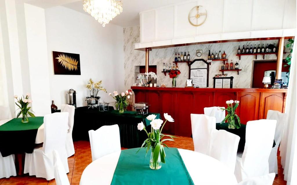 a restaurant with white tables and white chairs at Hotel Bursztyn in Kalisz