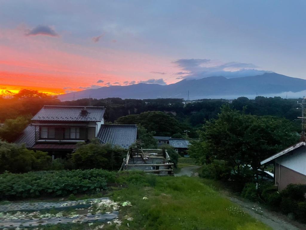 Asama Vista quiet home with view, Foreign Hosts في Miyota: غروب الشمس فوق قرية مع جبل في الخلفية