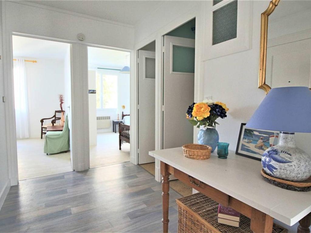 - un salon avec une table et un vase fleuri dans l'établissement Appartement lumineux pour famille à Royan, quartier calme près du marché, balcon et parking gratuit - FR-1-738-26, à Royan