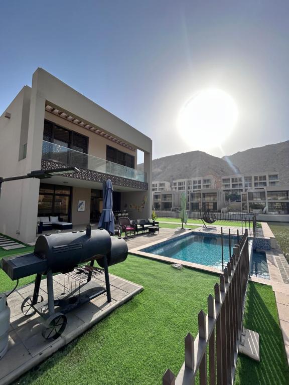 une maison avec une piscine et un fusil sur la pelouse dans l'établissement Nameer bay, à Bandar Jişşah