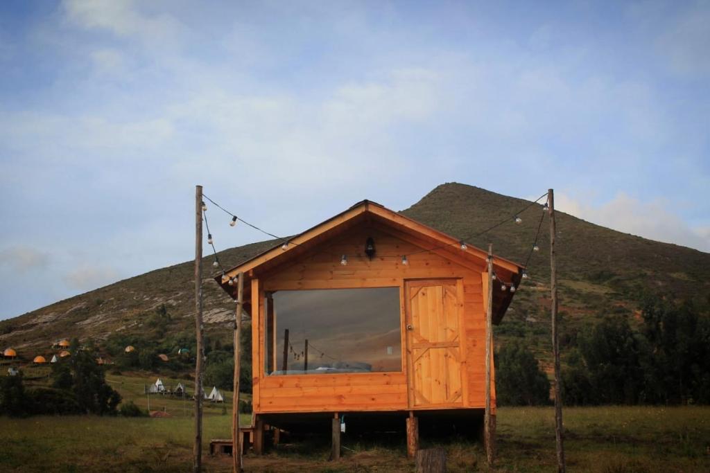 una pequeña casa con una gran ventana en un campo en Camping & Cabaña San Francisco - Guatavita, en Guatavita