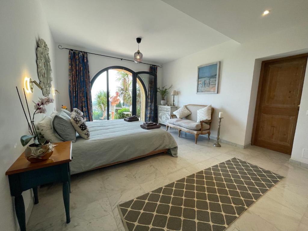 een slaapkamer met een bed, een stoel en een raam bij Luxury villa in Vence with panoramic sea views in Vence