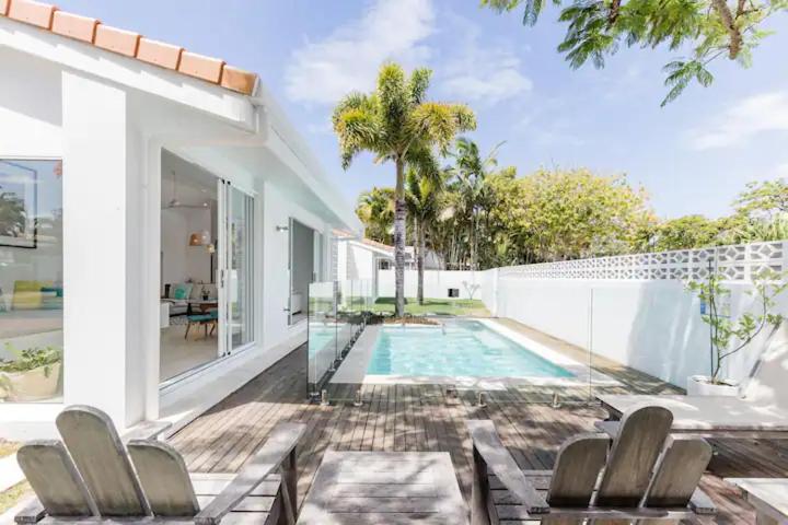 dom z basenem i patio z krzesłami w obiekcie Poinciana House—Luxury Noosa Retreat close to Beach w mieście Noosa Heads
