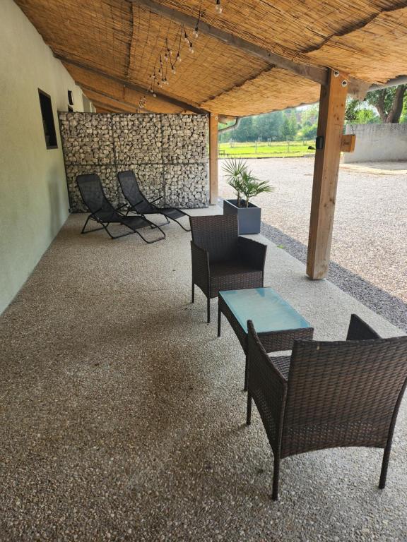 un patio avec des chaises et des tables ainsi qu'un mur en pierre dans l'établissement Gite La Charme avec spa, 