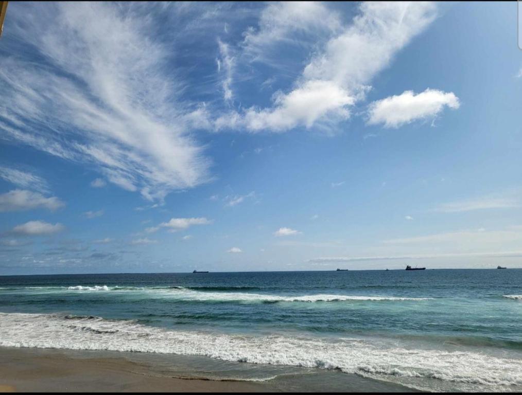 a beach with the ocean and a blue sky and clouds at Stunning oceanfront condo on usable Sandy Beach in Rosarito
