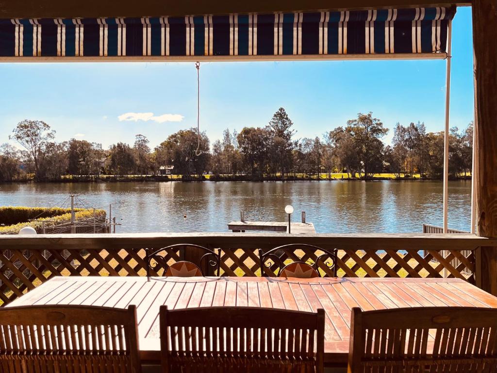 a view of a lake from a deck with a table and chairs at The Anchorage- A waterfront 70’s retreat in Dora Creek