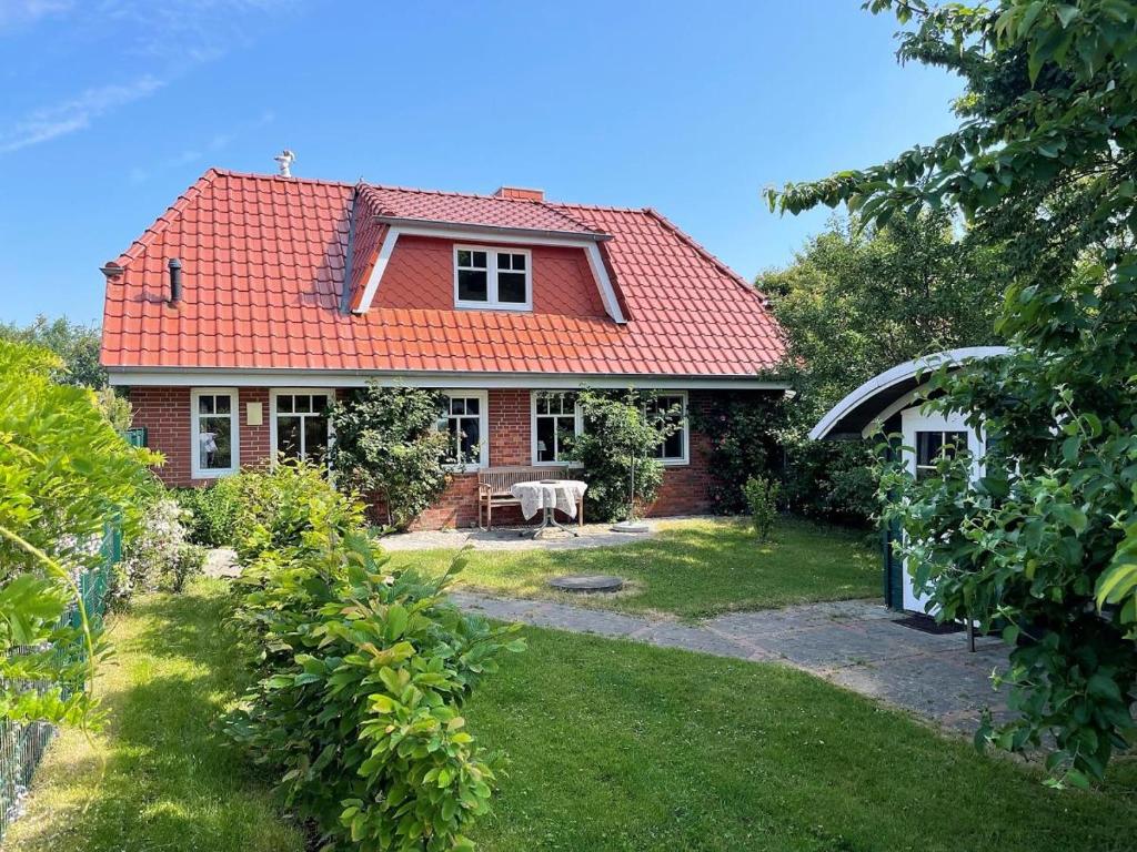 een stenen huis met een rood dak en een tuin bij Haus Benninghusumer Deichweg, eingezäunt, Hunde Willkommen, Kamin, ruhig gelegen, WLAN in Emmelsbüll-Horsbüll