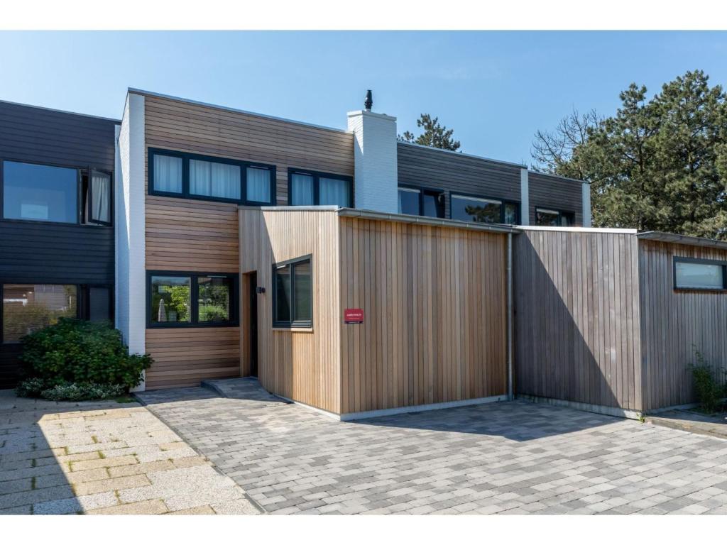 a house with a wooden fence in front of it at Attractive holiday home, sunny garden, 150 meters from the beach in Nieuwvliet-Bad