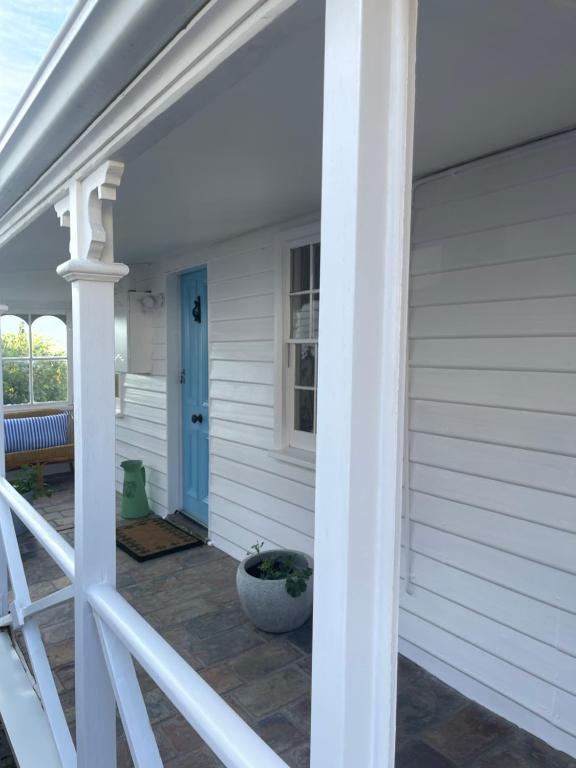 a porch of a white house with a blue door at Heritage Cottage in Sandy Bay in Sandy Bay