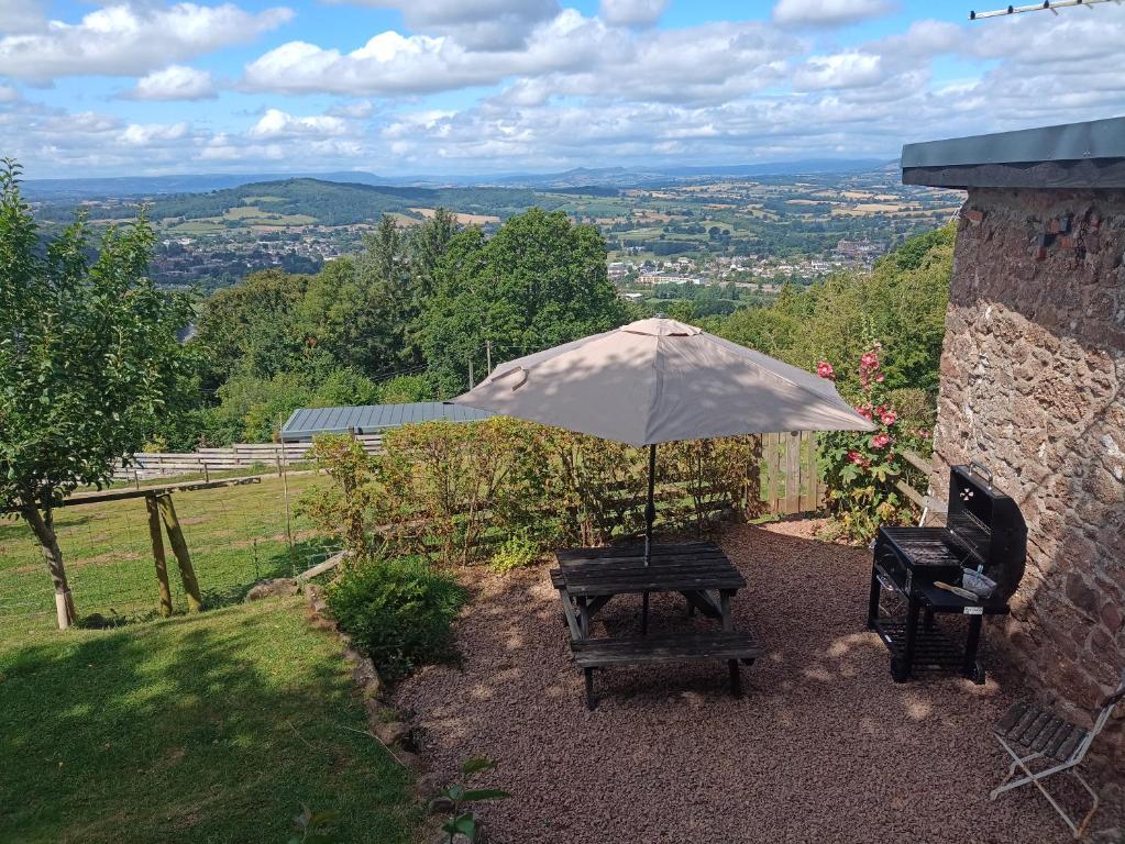 a bench with an umbrella in a garden at Top Barn WALES in Monmouth