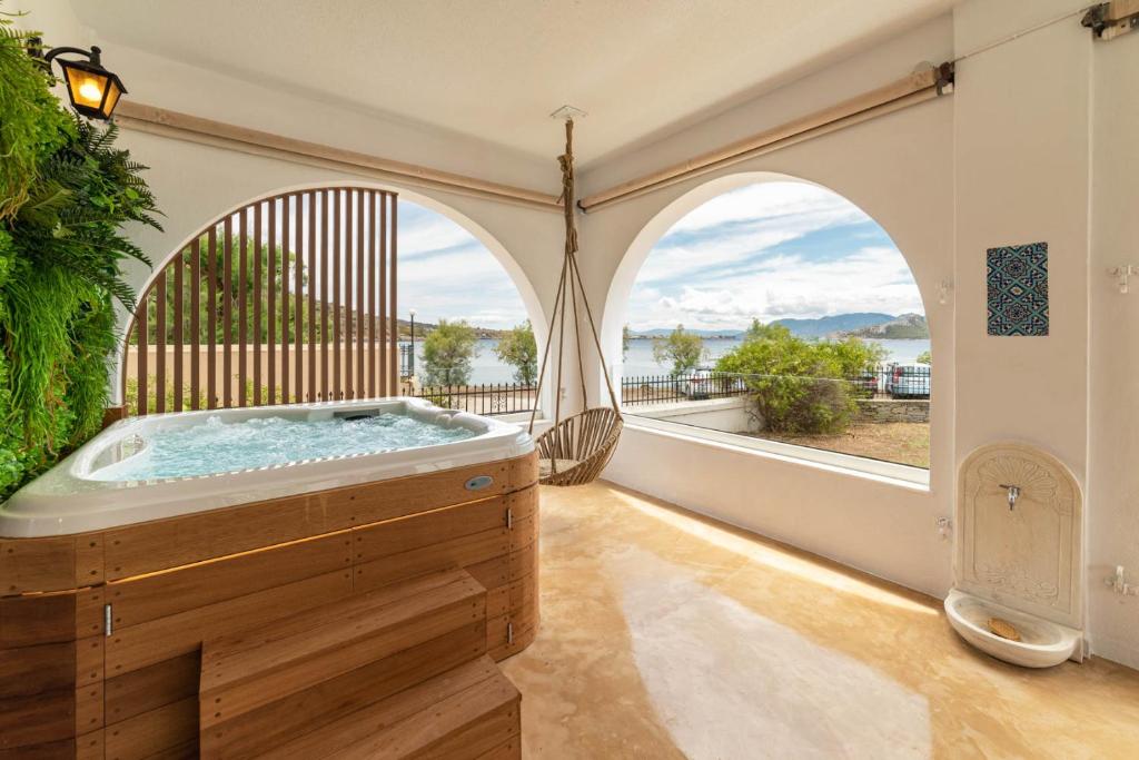 una vasca idromassaggio in una camera con una grande finestra di Faidon's Luxury House with jacuzzi by AegianKazarte a Kapótidhes
