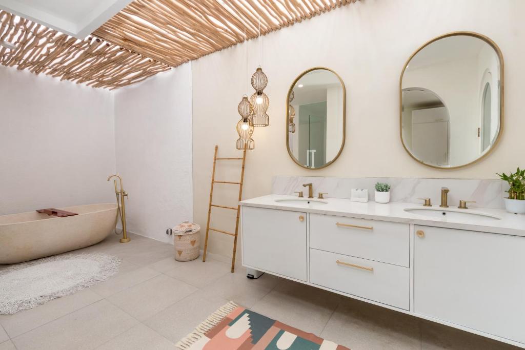 a bathroom with two sinks and a tub and mirrors at Villa Weiss Berawa in Canggu