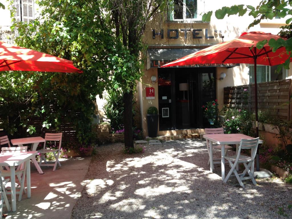 un patio con mesas y sombrillas frente a un edificio en Hôtel L'Eau Des Collines, en Marsella