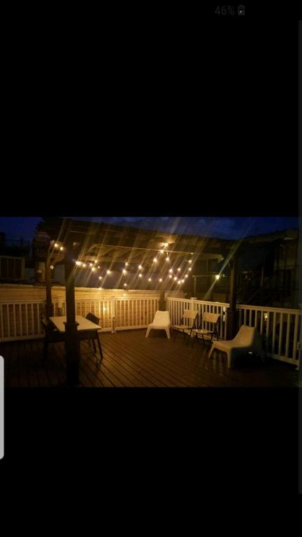 a deck with lights and tables and chairs on a porch at Fleet st Property in Baltimore