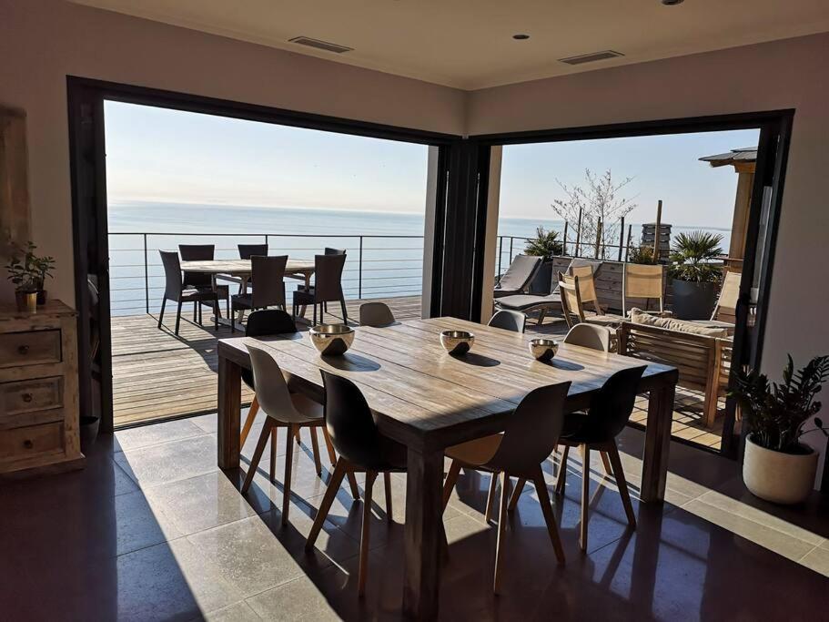 a dining room with a table and chairs on a balcony at Villa 10 p.Brando 170 m2 vue mer panoramique in Brando