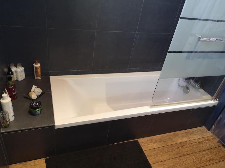 a white bath tub in a bathroom with black tiles at Villa 10 p.Brando 170 m2 vue mer panoramique in Brando