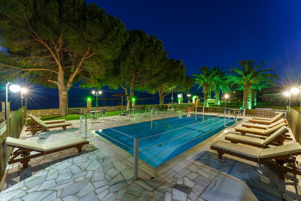 una piscina notturna con sedie e alberi di Nefeli Studios a Eratini