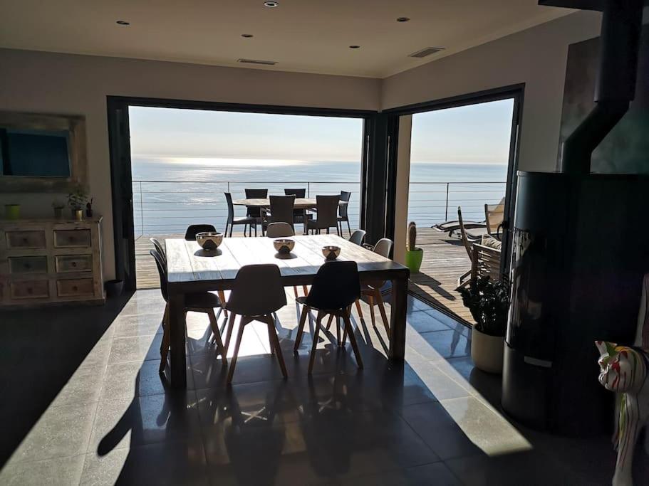 a dining room with a table and chairs and a balcony at Villa 10 p.Brando 170 m2 vue mer panoramique in Brando