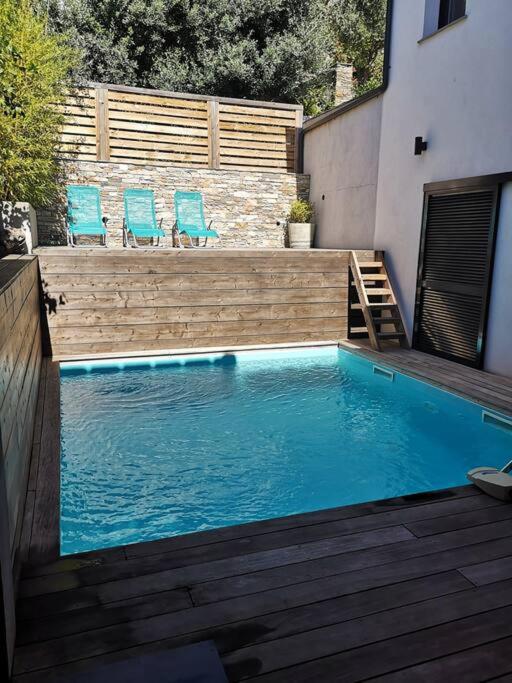 a swimming pool with two chairs and a wooden deck at Villa 10 p.Brando 170 m2 vue mer panoramique in Brando