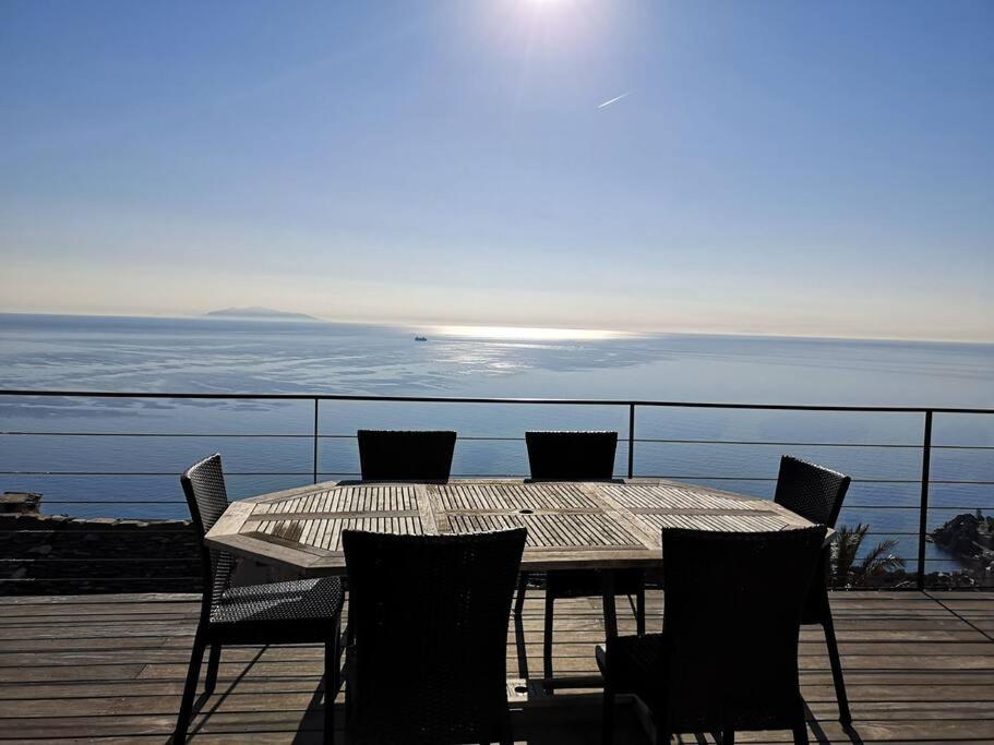 a wooden table and chairs on a deck with the ocean at Villa 10 p.Brando 170 m2 vue mer panoramique in Brando