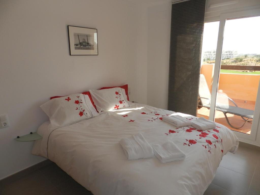 um quarto com uma cama branca com flores vermelhas em Apartment La Isla Terrazas de la Torre I em Roldán