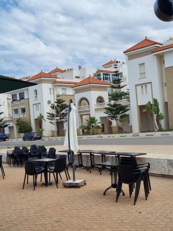 a group of tables and chairs with an umbrella at Appartement Al hoceima in Al Hoceïma