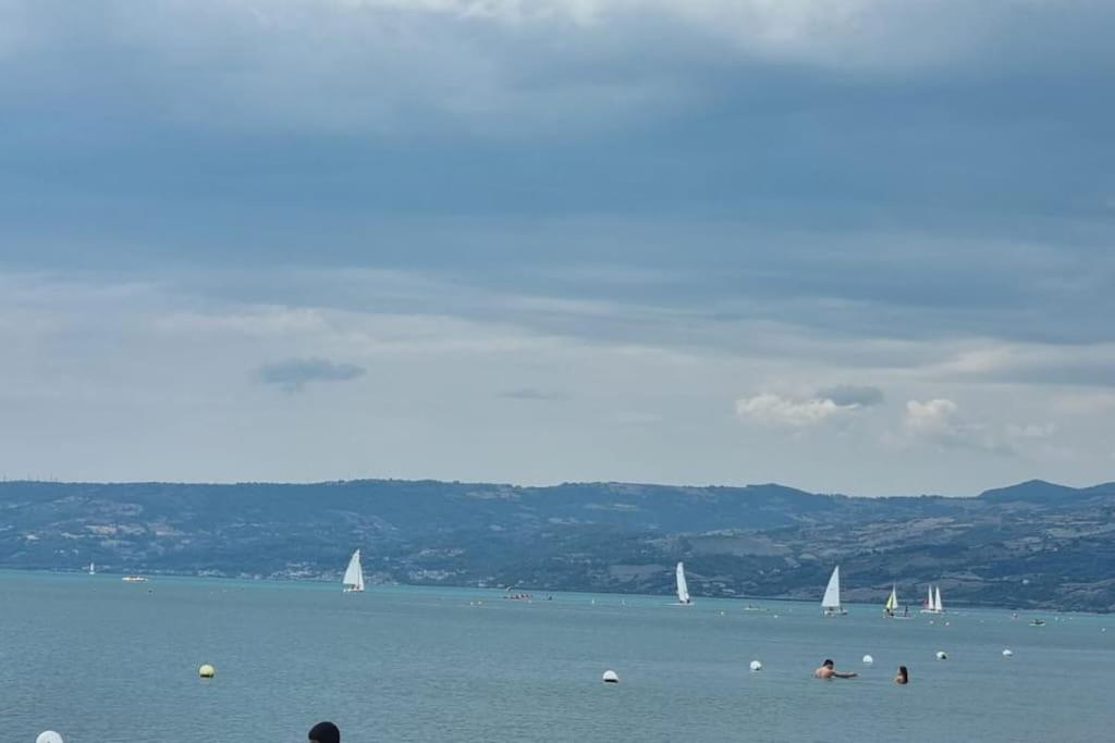 a group of people swimming in the water with sailboats at Appartement idéal pour découvrir le Sud d'Italie in Nova Siri Marina