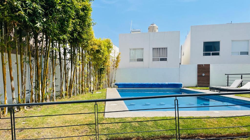 a swimming pool in front of a building with trees at Acogedora y amplia casa, alberca climatizada previa reserva in Juriquilla