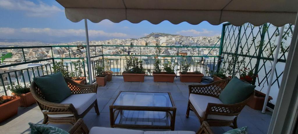 een balkon met stoelen en een tafel en uitzicht op de stad bij Taratsaki in Athene