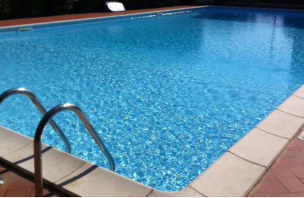 una gran piscina azul con agua azul en Airport at 25 min by walk - 5 min by walk to commercial center 2 min by walk to touristic port for trip to islands 5 min by walk to bus for city and beaches -Balcony sunset and Sea view-wi fi-air cond-5 persons-pool from 15 june to 15 september PISCINA en Olbia