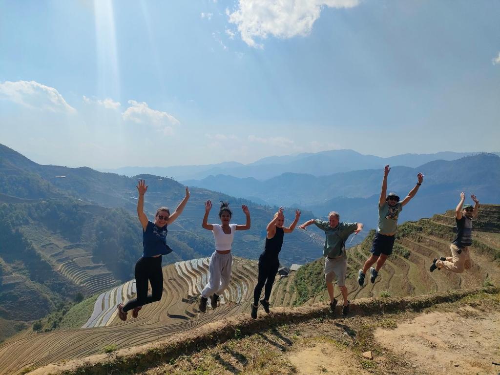 un grupo de personas saltando en la cima de una montaña en Indigenous homestay 1- Trek- Vegetarian- Bus en Mù Cang Chải