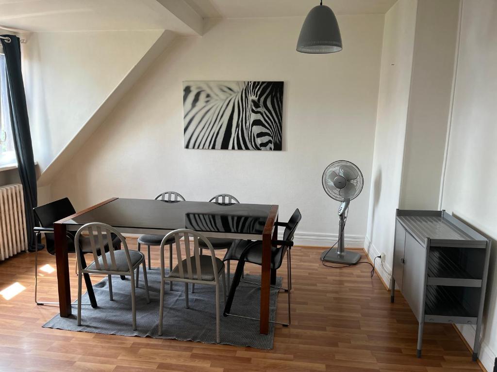 ein Esszimmer mit einem Tisch und Stühlen sowie einem Zebra-Gemälde in der Unterkunft Mury 3 in Straßburg