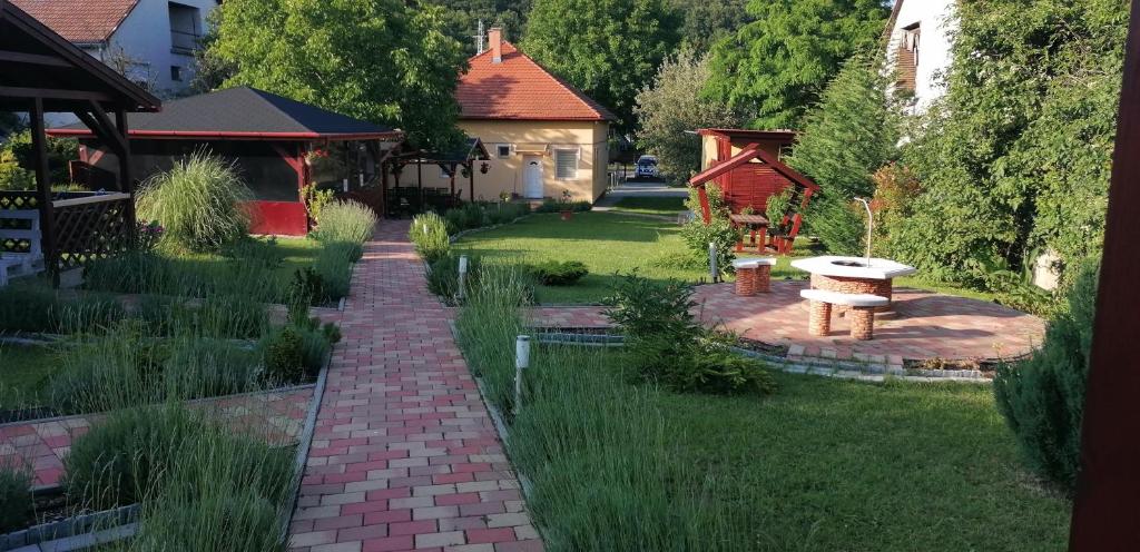 un jardín con un sendero de ladrillo y un banco en Ilona Prémium Vendégház - Kismaros en Kismaros