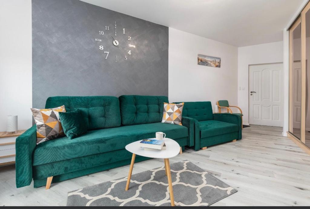 a living room with a green couch and a table at Apartament Hexagon nr 10 in Grzybowo