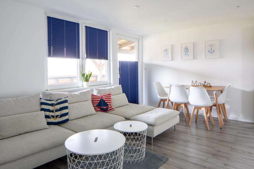 Una sala de estar con un sofá, una mesa y sillas. en Ferienhaus Annika in Schillig-Horumersiel mit 8 modernen Wohnungen, en Schillig
